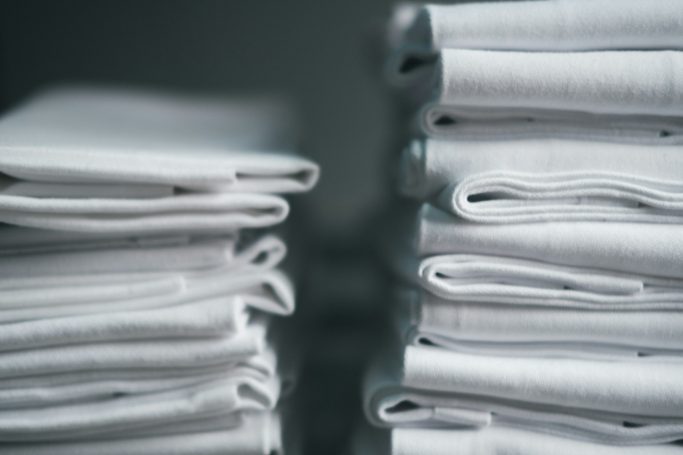 Neatly stacked white towels on a dark background.