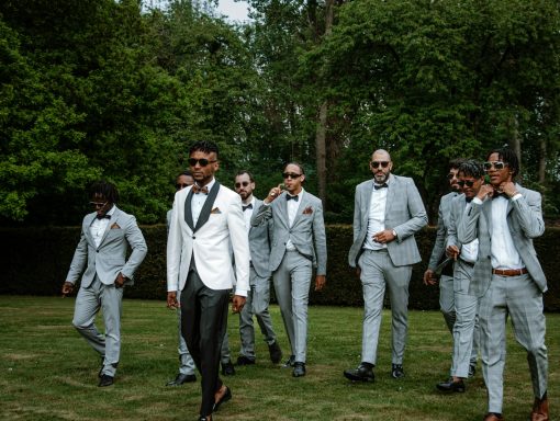 A group of men in grey suits walking together in a garden setting.