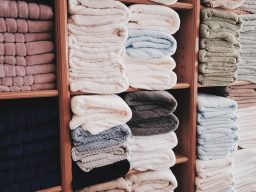 Pressed & Fresh | Neatly stacked towels in various colours on wooden shelves.