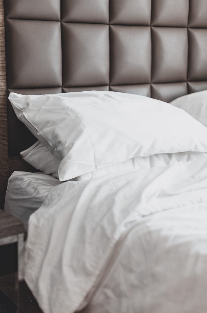 White pillows and bed linen on a bed with a tufted brown headboard. Pressed & Fresh take care of your bedding wash at affordable prices.