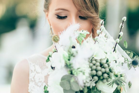 Bride holding a lush bouquet, with a soft focus background and gentle lighting.