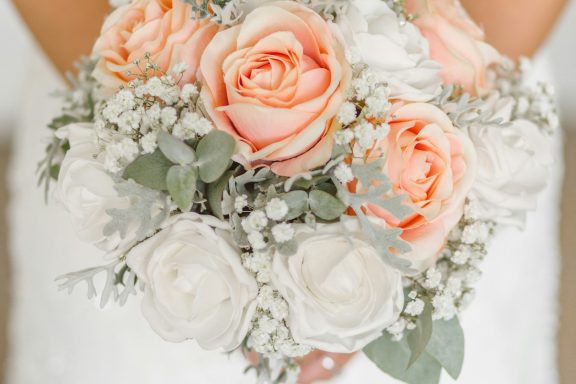 Bouquet of soft pink roses and white flowers with greenery.