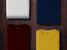 Pressed & Fresh | Four folded t-shirts in white, navy, burgundy, and yellow on a wooden surface.