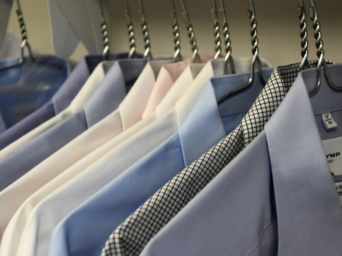 Pressed & Fresh | A row of neatly hung shirts in various shades of blue and white.