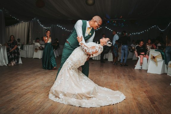 A groom dips his bride during their wedding dance in an elegantly decorated venue.